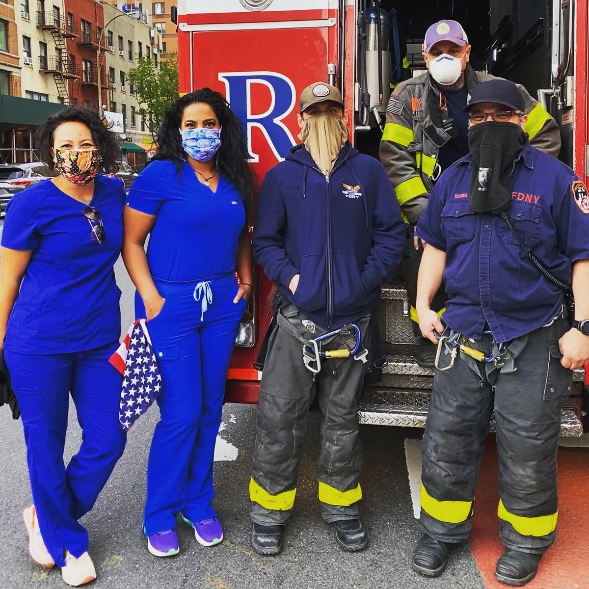 Two nurses standing with an FDNY crew beside their engine